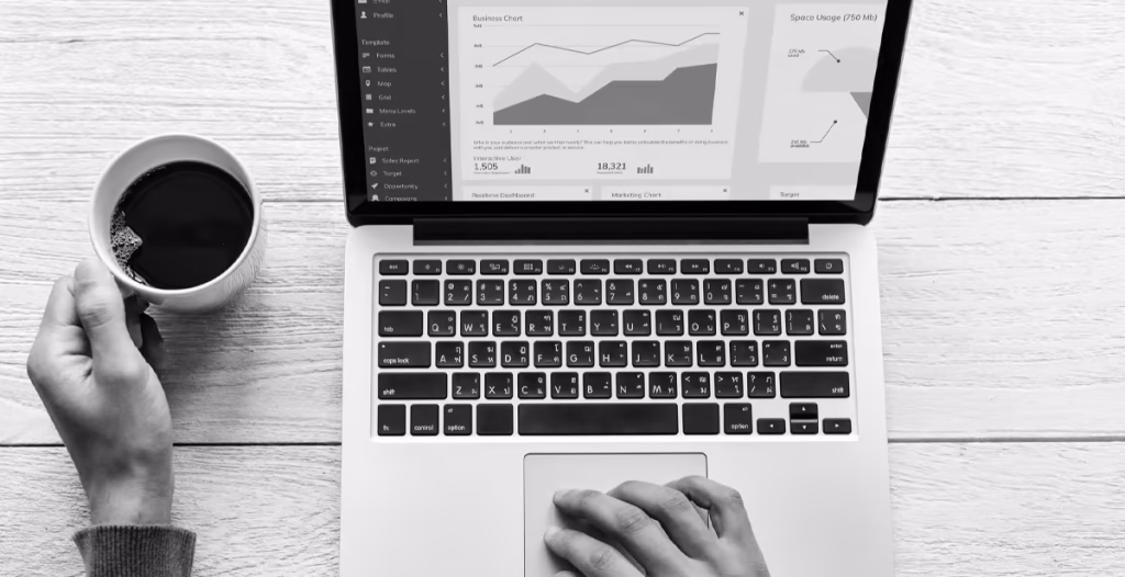 Top view of a person working on a laptop with analytics dashboards, holding a cup of coffee, representing WordPress SEO analysis and performance tracking.
